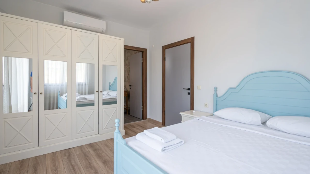 Açık renk mobilyalı, geniş dolaplı modern yatak odası