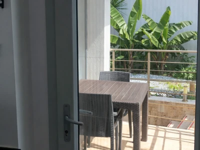 Balkon çıkışı, masa ve muz ağaçları manzarası